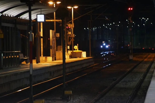 夜間の鉄道線路 夜間の鉄道駅のプラットホームは カーブに入ってくる列車で — ストック写真