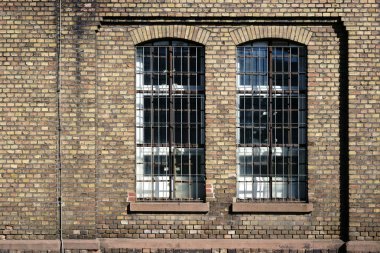 Disused factory with brick walls / A brick wall on the disused industrial site of an old factory with a barred window