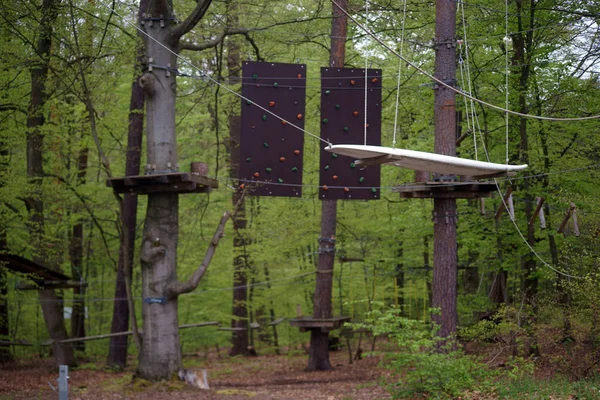 Obstacle course in the climbing forest / An obstacle course with climbing walls and a free swinging surfboard in a climbing forest surrounded by trees