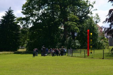 Heykel büyük yarım ayak Bad Homburg/bir grup insan sanat sergisi ve Heykel Bienali Blickachsen Haziran 09, 2019 Bad Homburg içinde spa bahçeleri sanatçı Fredrik sefil tarafından heykel büyük yarım ayak etrafında ayakta.