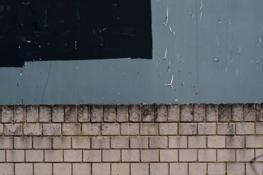 Gri billboard ve duvar kenarı / Parlak bir duvar kenarı üzerinde yırtık kağıt parçaları ile gri bir billboard yakın çekim