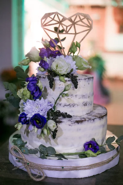 wedding two-tiered white cake with flowers and a decorative heart