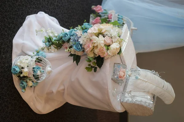 wedding rings in a glass box with stones, a decorative box, glasses, a pen in an inkwell on a table decorated with a pink cloth and flowers