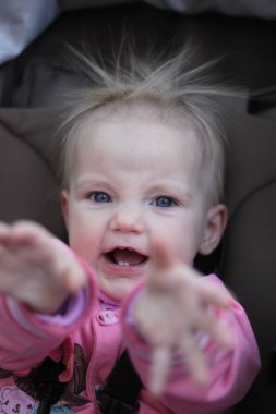 elektrikli saçlı pembe takım elbiseli küçük kız gülümsüyor ve yüzler yapıyor