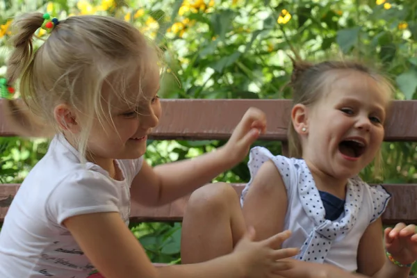 Két Lány Játszik Nevetni Egy Padon Kertben — Stock Fotó