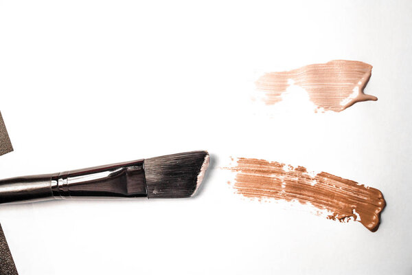 smear of foundation and black makeup brush