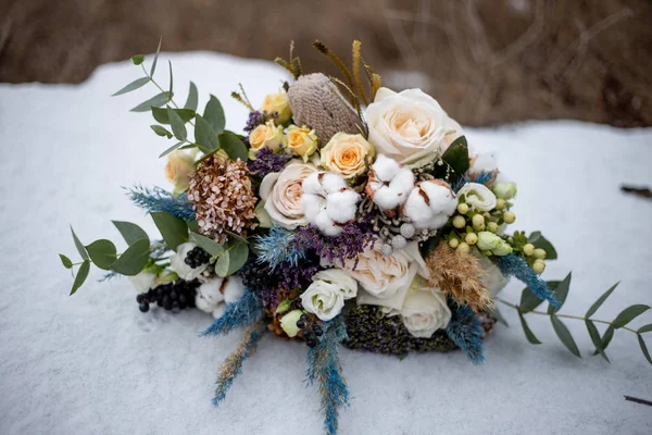 bouquet of roses and cotton flowers in the snow