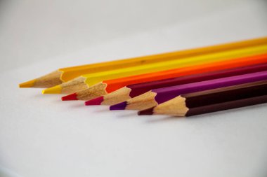 altı adet çok renkli kalem, beyaz yaprağa bir satırda yatıyor