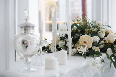 beyaz gül, şakayık, dahlias ve okaliptüs dalları ve başucu masada mumbir buket