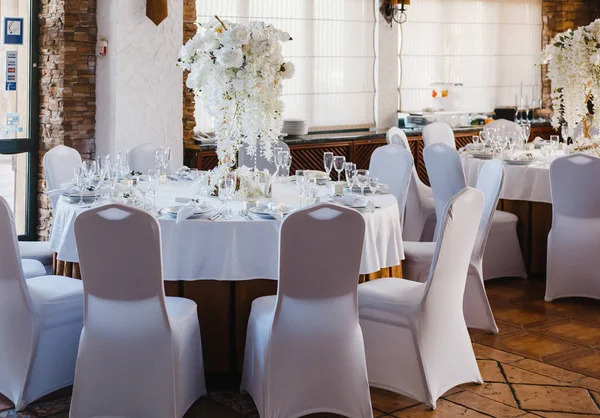 banquet round tables, decorated with a bouquet of white flowers in the center of the tables