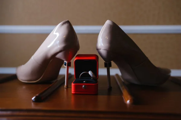 women\'s shoes and wedding rings in a box on a wooden tabletop