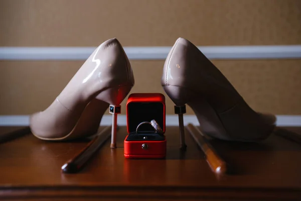 women\'s shoes and wedding rings in a box on a wooden tabletop