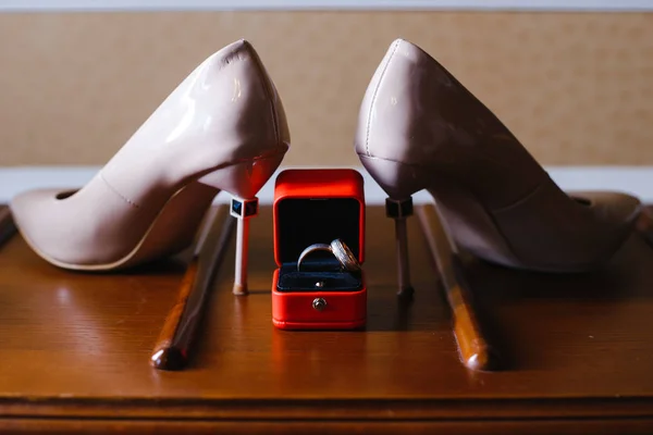 women\'s shoes and wedding rings in a box on a wooden tabletop