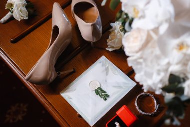 düğün aksesuarları: gelin buketi, iki ilik, kadın ayakkabıları, bir kutu içinde alyans, kadın bilezik, bir düğün davetiyesi ile zarf