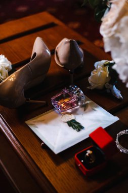 düğün aksesuarları: gelin buketi, iki ilik, kadın ayakkabıları, bir kutu içinde alyans, kadın bilezik, bir düğün davetiyesi ile zarf, parfüm