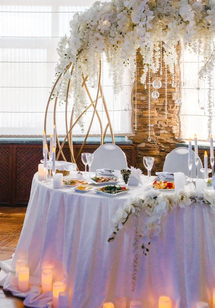 Yuvarlak bir ziyafet masası. Arkasında beyaz çiçekler olan kemer.