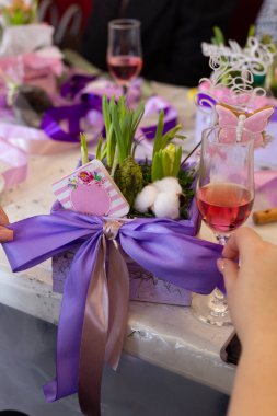 Kare bir saksıya sümbüllerle yay bağlayan kadın.