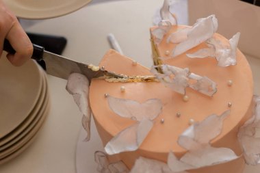 Kadın, yenilebilir inciler ve kelebeklerle süslenmiş bir pasta kesiyor.