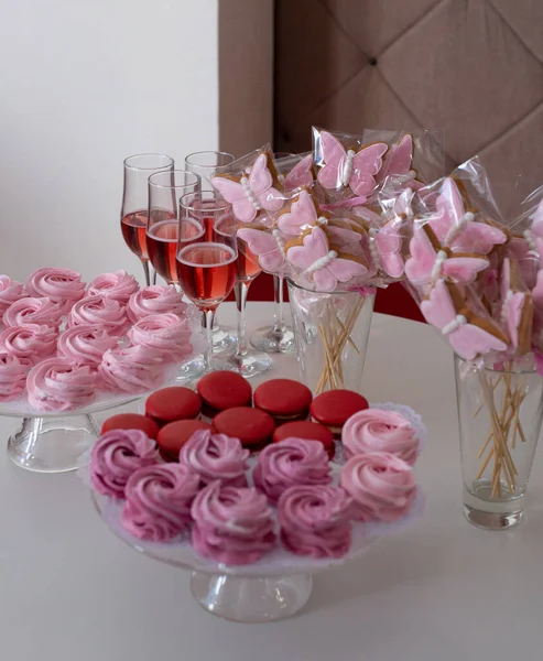 テーブルの上のお菓子 グラスコースターのメレンゲとマカロン グラスの蝶クッキー ピンクシャンパンのグラス — ストック写真