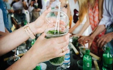 Kadın plastik bardağın kapağını mojito ile kapatıyor.