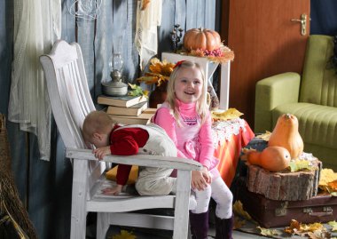 Cadılar Bayramı süslemelerinde bir sandalyede oturan iki kız kardeş.