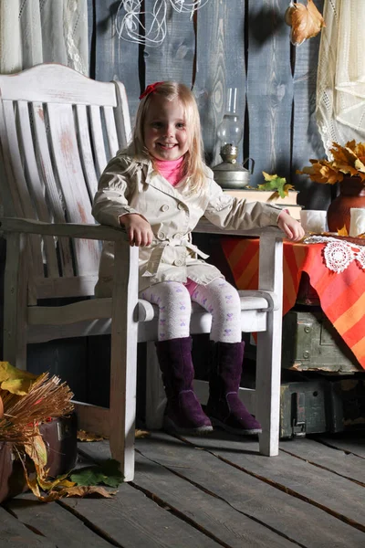 女孩坐在椅子上 坐在装饰品之间 微笑着 做鬼脸 — 图库照片