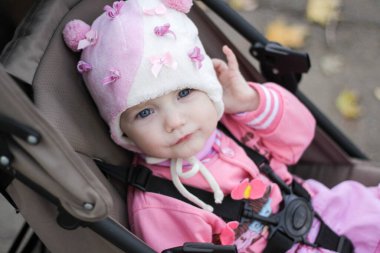 Pembe elbiseli küçük kız bebek arabasında