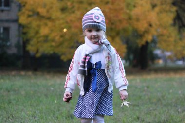 Beyaz ve mavi elbiseli kız doğanın arka planında poz veriyor.