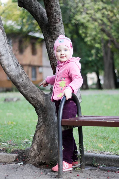 Una Chica Rosa Para Cerca Banco Del Parque —  Fotos de Stock