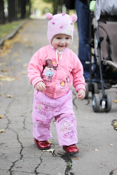 穿着粉色衣服的小女孩正在秋天的公园里散步 — 图库照片