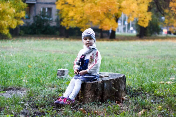 Uma Menina Senta Toco Árvore Parque Outono Sorri Faz Rostos — Fotografia de Stock
