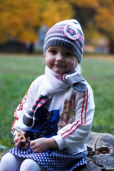 Uma Menina Senta Toco Árvore Parque Outono Sorri Faz Rostos — Fotografia de Stock