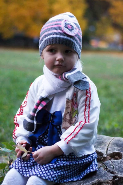 Uma Menina Senta Toco Árvore Parque Outono Sorri Faz Rostos — Fotografia de Stock