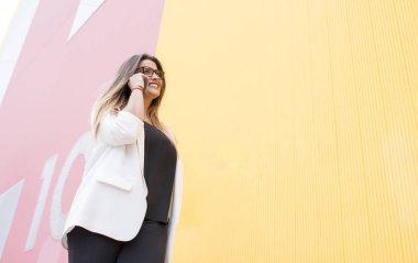 Hareket eden telefon içinde pembe ve sarı duvar ile yakışıklı genç kadın