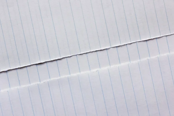 A ripped page of a lines notebook rests on the notebook itself , top view ,