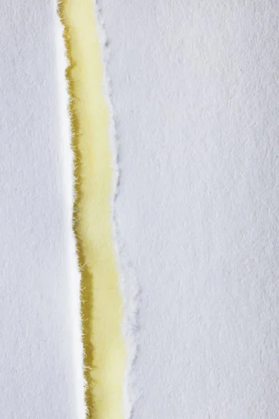 A white ripped paper rests on a yellow background ,beautiful paper edge , top view