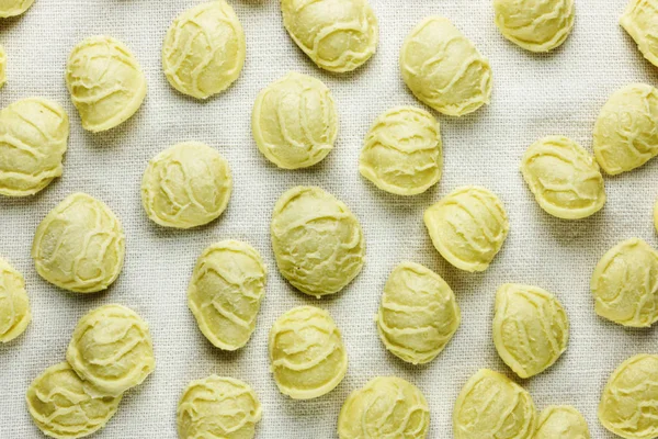 Orecchiette pasta on a white cloth ,a small ear shape pasta with the center thinner than the edge  and a rough surface