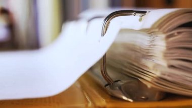 Sarı yüzük klasörünün sayfalarını çevirmek, Pembe kalemle bir sayfanın altını çiz, ön plandaki çelik halka klasöründe, odak kitaplarından ve klasörlerden arkaplanda