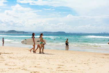 Gold Coast, Queensland, Avustralya - 21 Nisan 2015: güneşli bir günde sahilde yürüyüş sörf tahtaları iki kızla