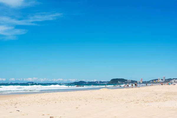 Gold Coast, Queensland, Avustralya - 2 Nisan 2015: güneşli meşgul gün sahilde güneş bronzluk elde ve okyanusta yüzmeye sörf tahtaları ile birçok kişi mayo ile