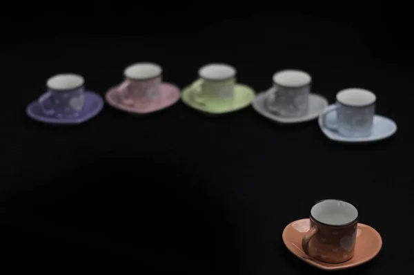 Lined up on a black background colorful coffee cups