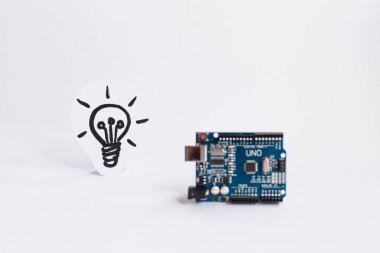Ternopil, Ukrayna - 19 Nisan 2019: Arduino Uno. Arduino. Mikro kontrolör. Teknoloji. Arka planda bir ampul resmi. Bilim. Beyaz arka plan.