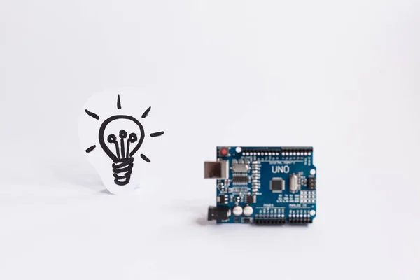 Ternopil, Ukrayna - 19 Nisan 2019: Arduino Uno. Arduino. Mikro kontrolör. Teknoloji. Arka planda bir ampul resmi. Bilim. Beyaz arka plan.