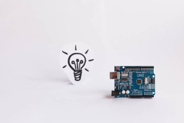 Ternopil, Ukrayna - 19 Nisan 2019: Arduino Uno. Arduino. Mikro kontrolör. Teknoloji. Arka planda bir ampul resmi. Bilim. Beyaz arka plan.