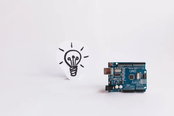 Ternopil, Ukrayna - 19 Nisan 2019: Arduino Uno. Arduino. Mikro kontrolör. Teknoloji. Arka planda bir ampul resmi. Bilim. Beyaz arka plan.