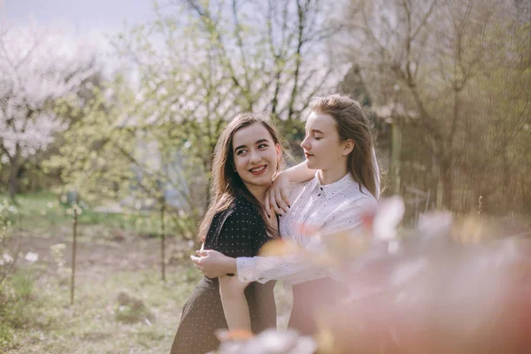 Porträt zweier hübscher junger Schwestern im grünen Frühlingsgarten — Stockfoto