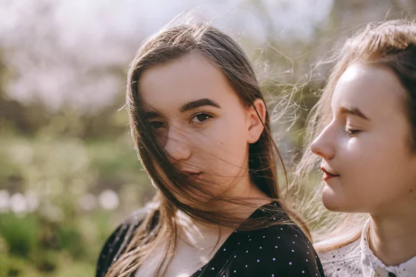 Portrét dvou krásných mladých sester v zelené jarní gardu — Stock fotografie