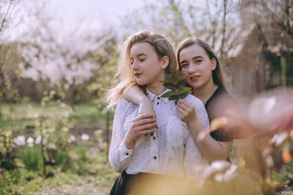 Portrét dvou krásných mladých sester v zelené jarní gardu — Stock fotografie