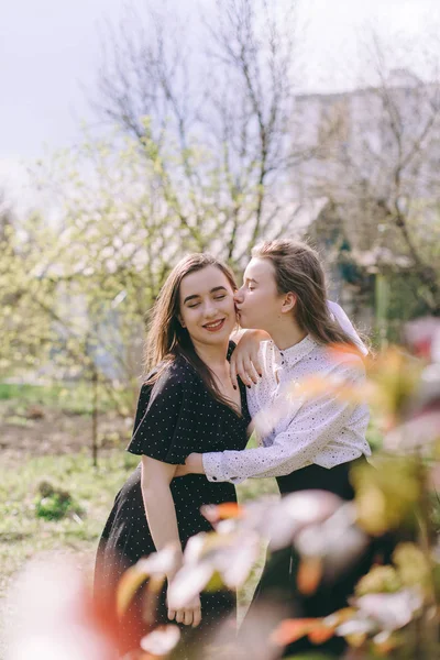 Glückliche Freundinnen bei Sonnenuntergang. Porträt zweier hübscher junger Schwestern im grünen Frühlingsgarten, die sich auf dem Feld in der Sonne umarmen. Gemeinsam Spaß haben, positive Emotionen, bunte Farben. Kopierraum — Stockfoto