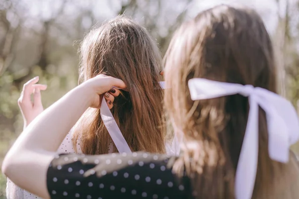 Porträt zweier hübscher junger Schwestern im grünen Frühlingsgarten, die sich auf dem Feld in der Sonne umarmen. Gemeinsam Spaß haben, positive Emotionen, bunte Farben. Kopierraum. glückliche Freundinnen bei Sonnenuntergang — Stockfoto